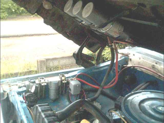 Open engine bay with blue inner fenders, red cables and round air cleaner, hood raised