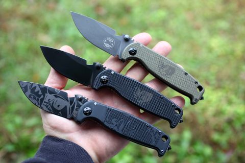 1984 Ford Bronco - A hand displays three folding knives, each with distinct blade finishes and handle designs.