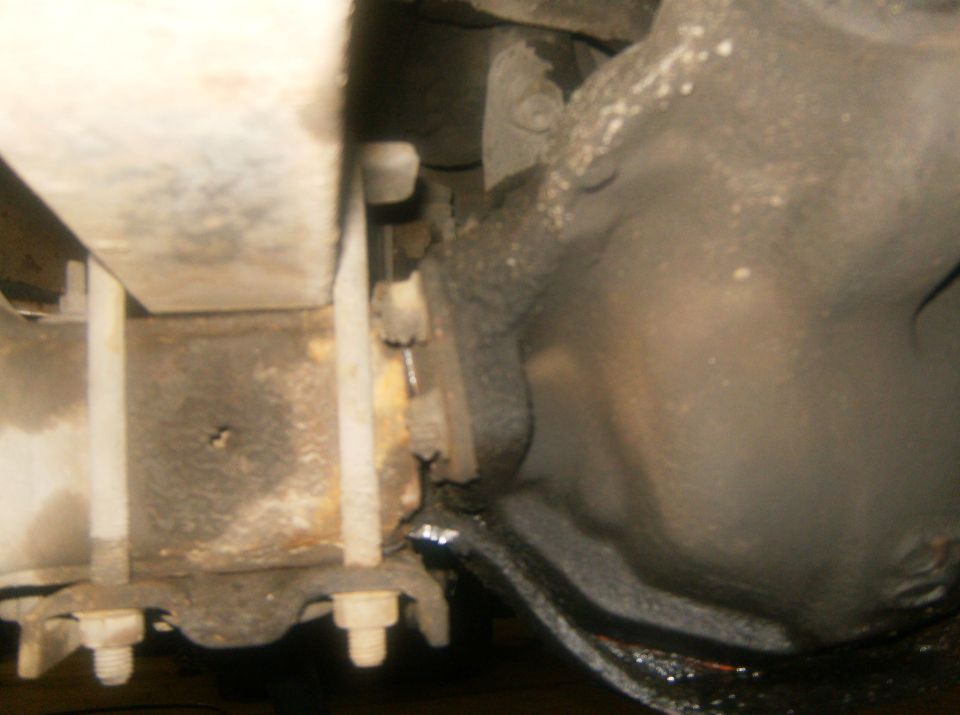 Close-up of rusty metal frame, bolts, and suspension parts under a vehicle
