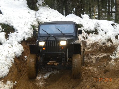 2005 Jeep Wrangler - A black Jeep Wrangler navigates a challenging muddy and snowy off-road path.
