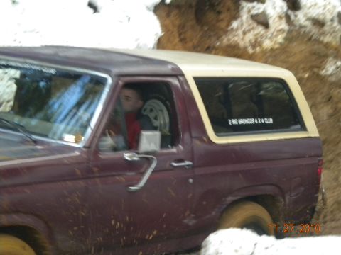 2005 Jeep Wrangler - A maroon Ford Bronco navigates a muddy off-road course.