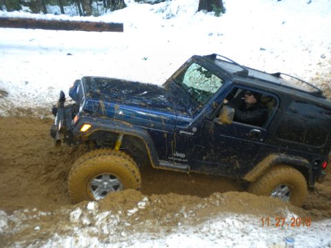 2005 Jeep Wrangler - A blue 2005 Jeep Wrangler navigates through a muddy, snowy terrain.