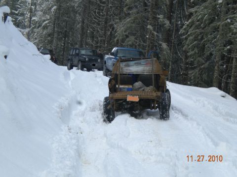 2005 Jeep Wrangler - A convoy of off-road vehicles navigates a snowy forest path, with a custom utility vehicle leading the way.