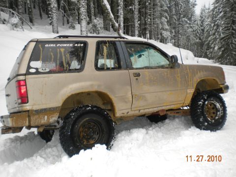 2005 Jeep Wrangler - A modified 2-door SUV is stuck in the snow, with mud splattered on its body.