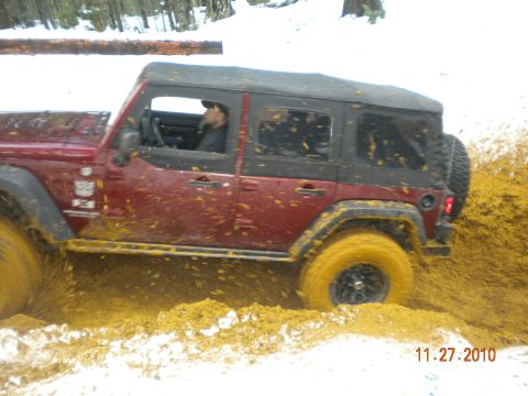 2005 Jeep Wrangler - A red Jeep Wrangler navigates a muddy trail in a snowy environment.