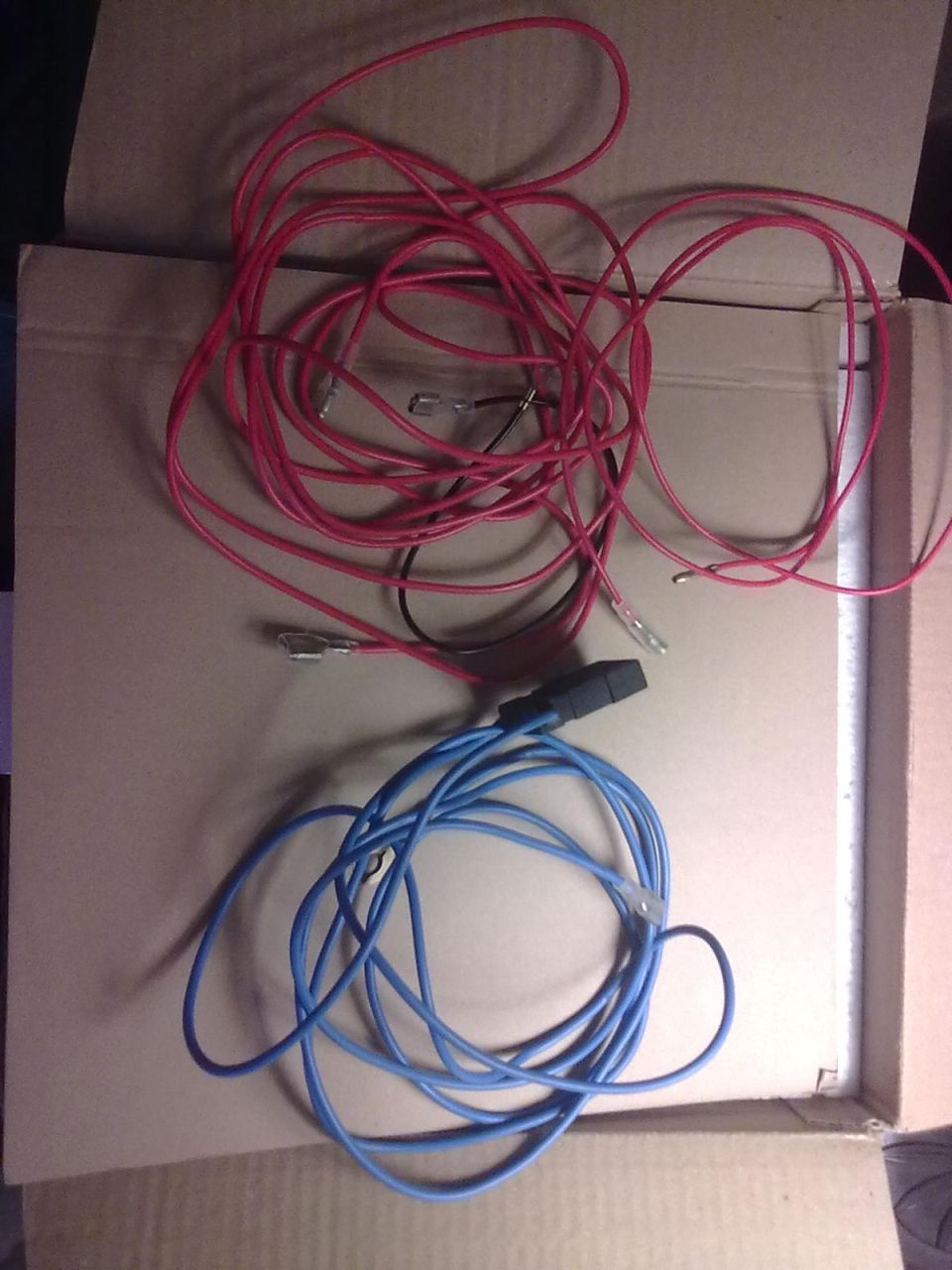 Tangled red and blue wires with connectors, lying on cardboard