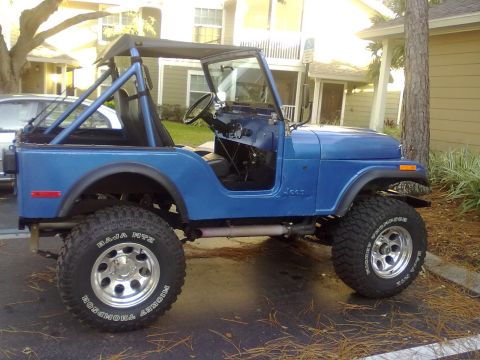 1978 Jeep CJ5 - This blue 1978 Jeep CJ5 is parked outdoors with a soft top and roll cage.