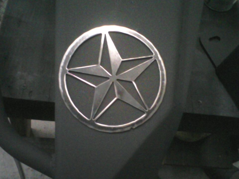 Bare metal nautical star emblem in a welded ring mounted on gray primered panel