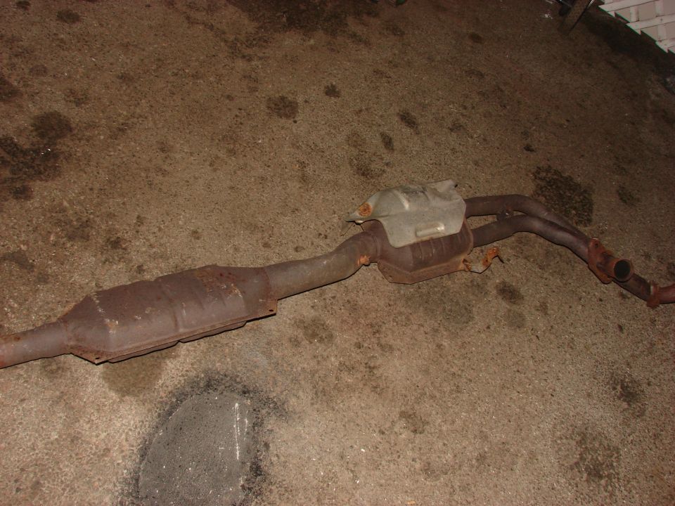 rusted exhaust pipe and catalytic converter on concrete