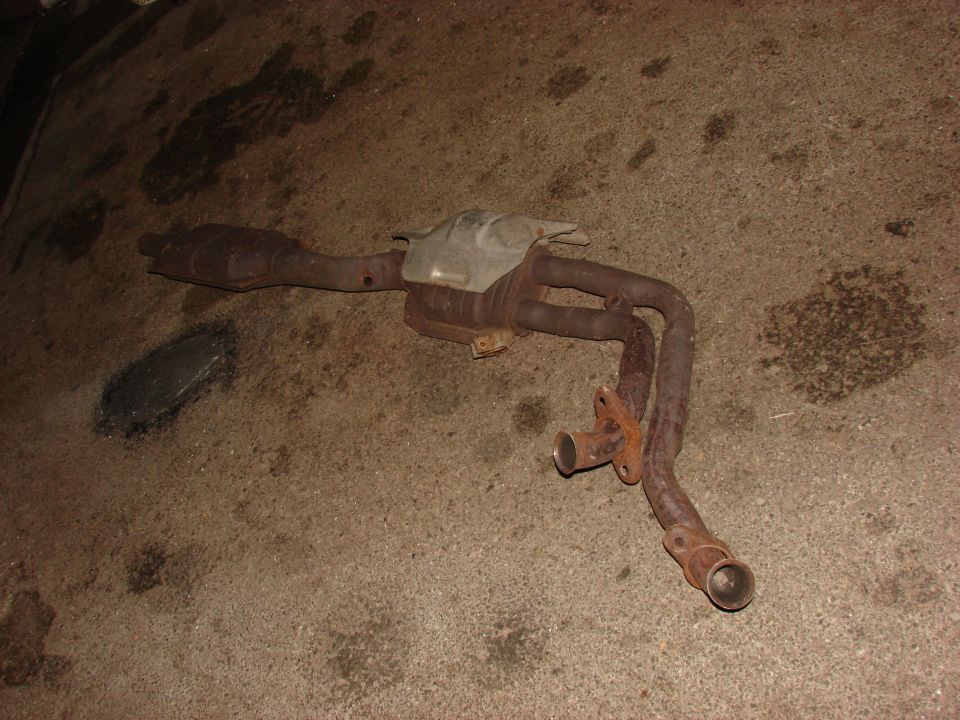 Rusty exhaust manifold and catalytic converter on concrete floor