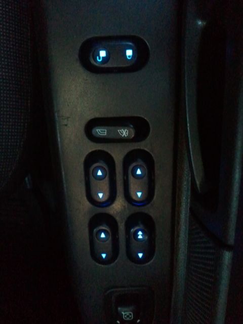 2003 Ford Crown Victoria - Close-up of illuminated power window controls on a vehicle's interior door panel.