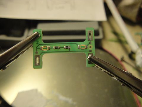 2003 Ford Crown Victoria - A circuit board is held by alligator clips, showing electronic components and some text.