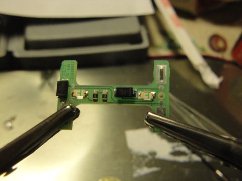 2003 Ford Crown Victoria - A circuit board with electronic components is being held by two sets of tweezers.