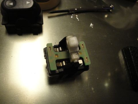 2003 Ford Crown Victoria - A disassembled car window switch assembly is shown on a workbench, with tools nearby.