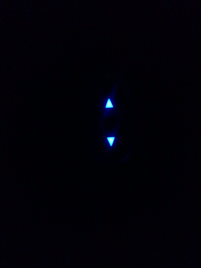 Two glowing blue arrow indicators, one pointing up, one down, on a dark surface