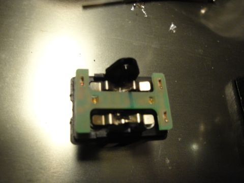 2003 Ford Crown Victoria - Close-up view of an electrical component, likely a switch or relay, with a green circuit board and exposed metal contacts.
