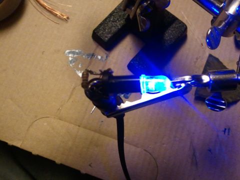 2003 Ford Crown Victoria - A close-up view of a soldering iron with a blue LED light attached, ready for electronic work.