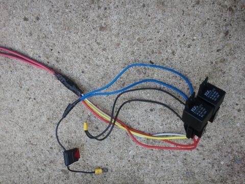 2003 Ford Crown Victoria - A close-up view of an automotive wiring harness, including relays and a switch, laid out on a concrete ground.
