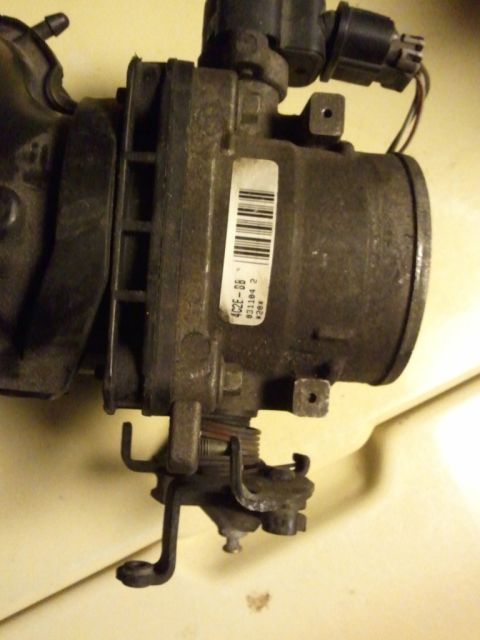 2003 Ford Crown Victoria - Close-up of a throttle body assembly, likely a replacement part, with visible part numbers on a sticker.