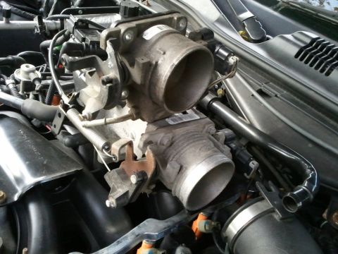2003 Ford Crown Victoria - Close-up view of a vehicle's engine throttle body assembly, showing mechanical components and wiring.