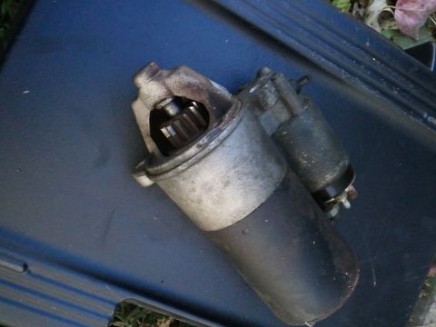 2003 Ford Crown Victoria - Starter motor part shown close-up on a dark blue surface.