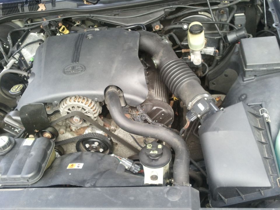 Engine bay of a 2003 Ford Crown Victoria, showing the engine cover, alternator, and air intake system