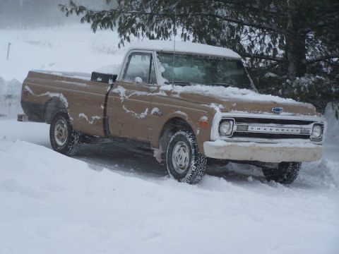 1969 Chevrolet C/K Pickup - A brown 1969 Chevrolet C/K Pickup truck is partially covered in snow, parked in a snowy landscape.