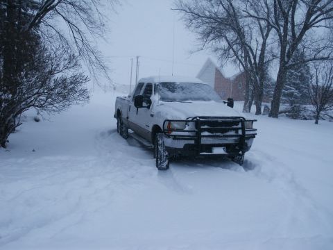 2000 Ford F-250 - White Ford F-250 pickup truck parked in deep snow during a blizzard.
