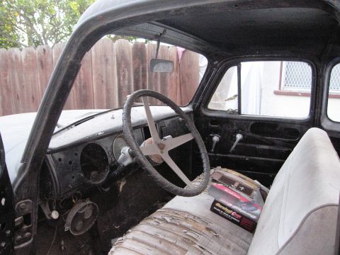 1986 Ford Bronco - The interior of an old truck shows a worn seat and a distinctive steering wheel, with parts missing from the dashboard.
