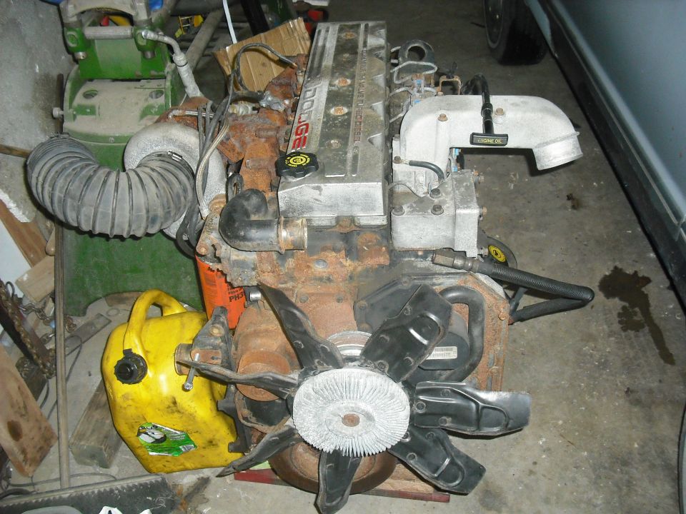 Dodge Cummins engine with turbocharger, fan, and yellow gas can nearby