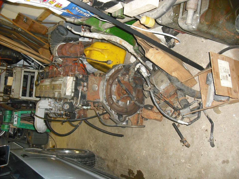 Engine and transmission assembly with various hoses and a yellow gas can nearby
