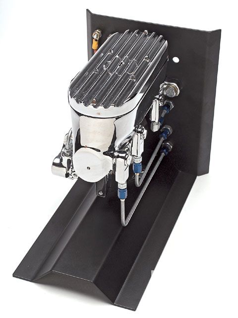 1990 Ford Bronco - A chrome brake master cylinder assembly with ribbed cap and blue-lined brake lines is mounted on a black bracket.