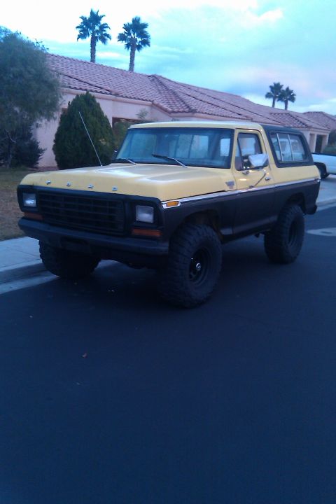 1979 Ford Bronco - This two-tone 1979 Ford Bronco features a yellow top half and black lower half, with prominent off-road tires.