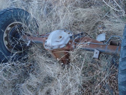 1977 Ford F-150 - Rear axle assembly, likely from a truck, sits in dry grass. The Supermotors.net logo is visible in the lower right corner.