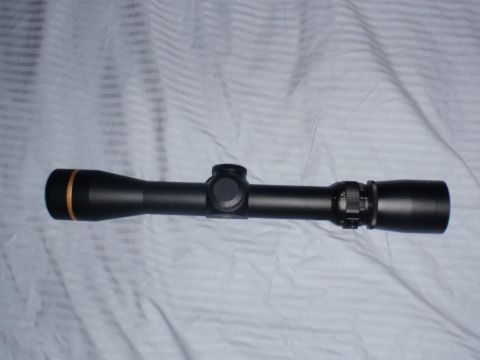 1991 Ford Bronco - A rifle scope is shown lying on a striped fabric surface.