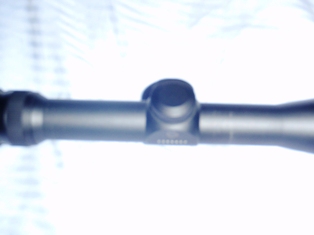 1991 Ford Bronco - Close-up of a rifle scope, showing its central body and adjustment knob.