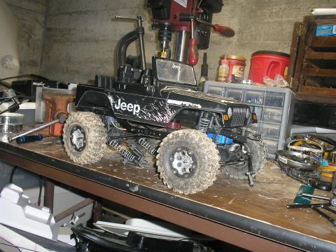 1994 Ford Escort - RC Jeep Wrangler toy is on a workbench with a drill press and storage drawers in the background.