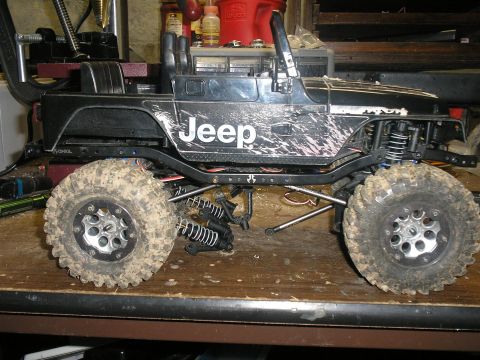 1994 Ford Escort - This is a remote control Jeep model with a black body, mud splatter, and large off-road tires, shown on a workbench.