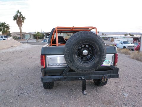 1982 Ford Bronco - Ford Bronco with aftermarket bumper and spare tire carrier, parked outdoors. Another truck is visible in the background.