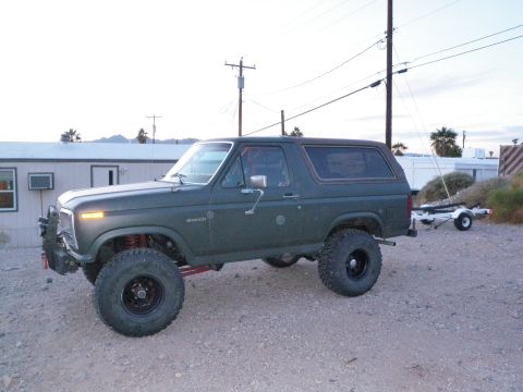 1982 Ford Bronco - A lifted 1982 Ford Bronco is shown from the side, parked outdoors with a trailer attached.