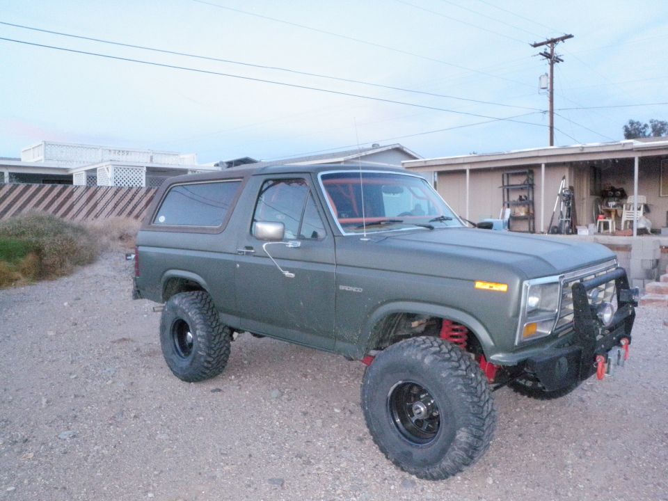 Olive green Ford Bronco with lifted suspension and off-road tires parked on gravel