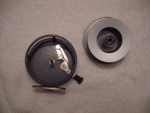 1990 Ford Bronco - Two parts of a fishing reel are laid out on a textured surface, showing internal mechanisms.