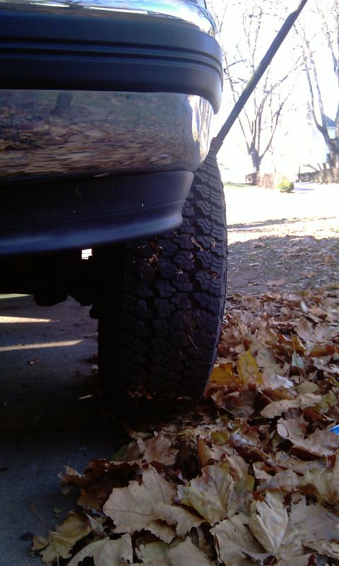 1993 Ford Bronco - A close-up view of a vehicle's rear tire and bumper, surrounded by fallen autumn leaves.