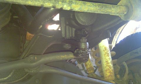 1993 Ford Bronco - Close-up view of the undercarriage reveals worn suspension components and a rusty shock absorber.