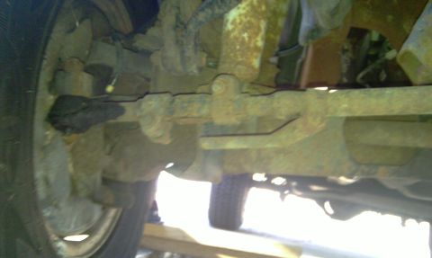 1993 Ford Bronco - The underside of a vehicle shows significant rust on the suspension components and a tire.