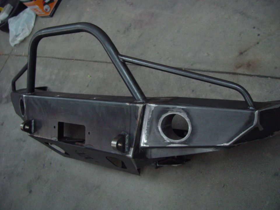 Unpainted steel custom bumper with brush guard, winch cutout, and tow hooks