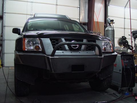 1993 Ford Bronco - Nissan Xterra with a custom front bumper and bull bar, parked in a workshop with welding gear.