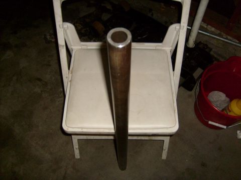 1986 Ford Bronco - A metal pipe is positioned vertically on a white folding chair in a dimly lit room.