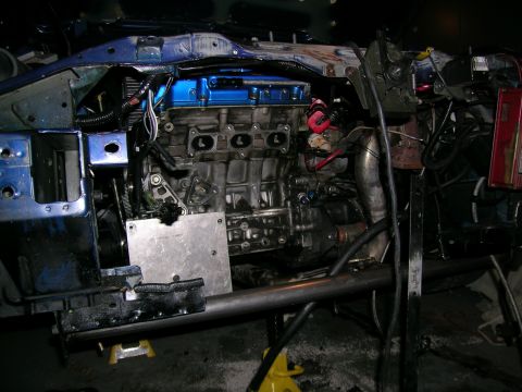 1995 Ford Probe - Engine bay of a car undergoing modification, with the engine exposed and the vehicle supported by jack stands.