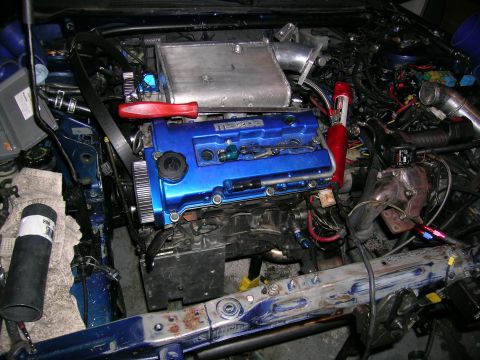 1995 Ford Probe - Close-up view of a modified engine bay a blue Mazda valve cover and custom intercooler piping.